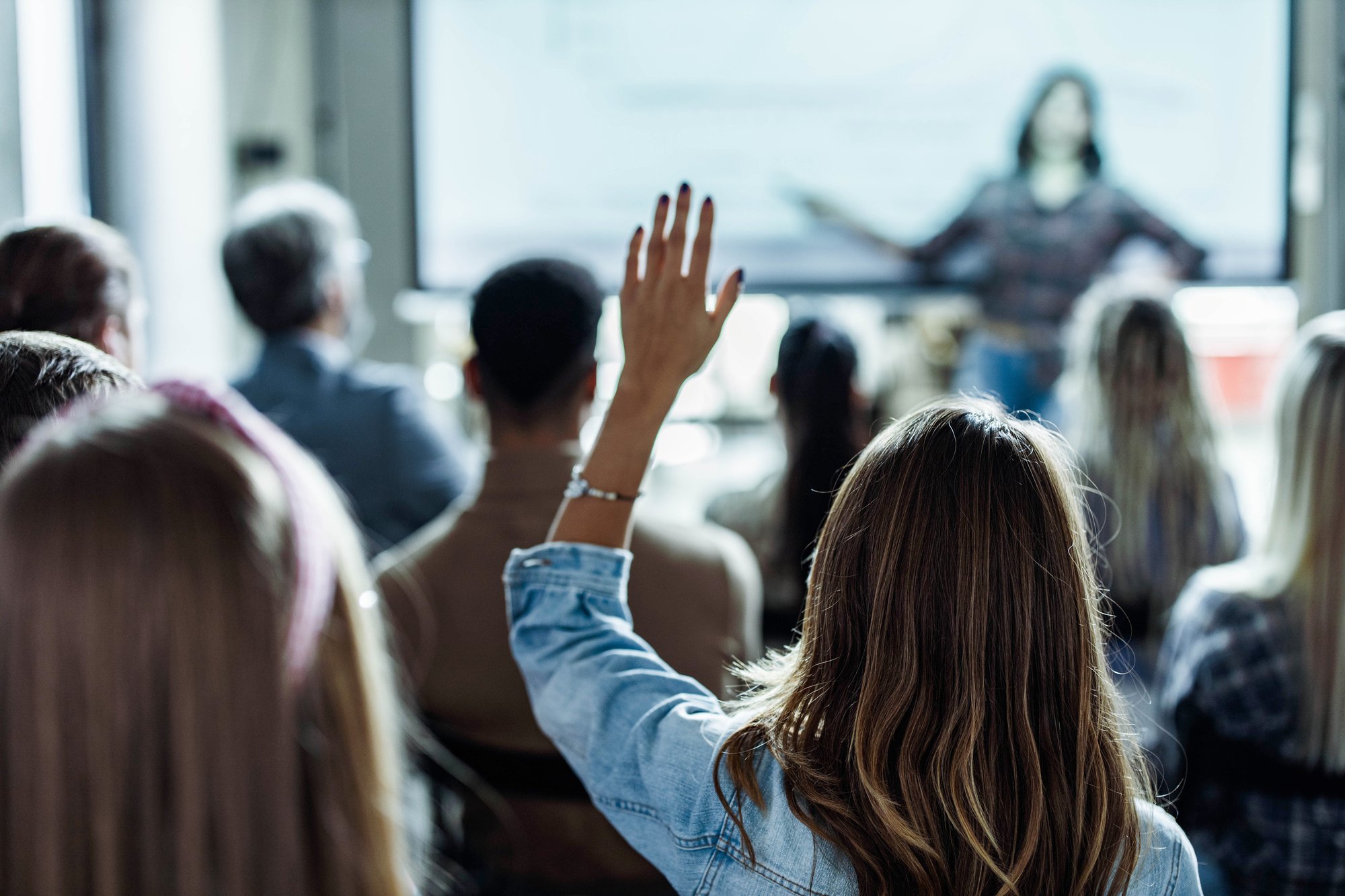 Crowd with a person raising her hand in class